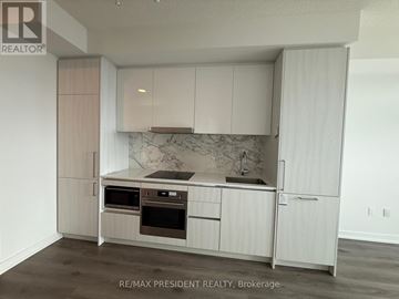 Vaughan (Vaughan Corporate Centre) condo for rent - A kitchen with white cabinets and a marble backsplash.