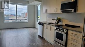 Hamilton (Beasley) condo for rent - A kitchen with white cabinets and a black microwave above the stove.