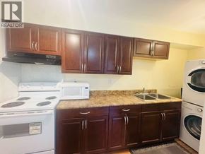 Coquitlam apartment for rent - A kitchen with brown cabinets and a white stove top oven.