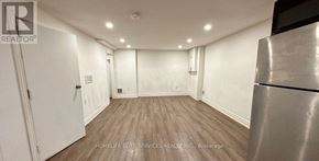 Ajax (Central West) apartment for rent - A spacious room with wooden flooring and white walls.