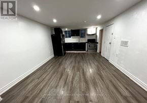 Ajax (Central West) apartment for rent - A spacious room with wooden flooring and a kitchenette in the background.
