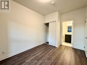 Clarington (Bowmanville) condo for rent - A room with wooden flooring and white walls, with a doorway leading to another room.