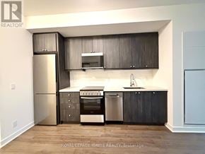 Clarington (Bowmanville) condo for rent - A modern kitchen with dark wood cabinets and stainless steel appliances.