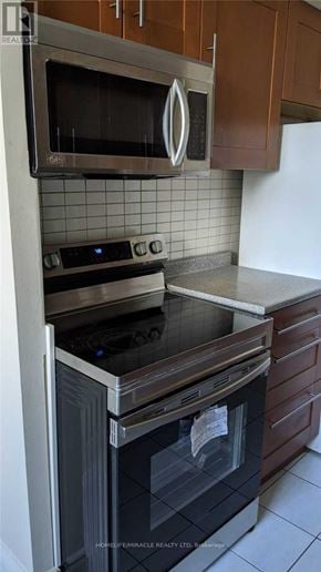 Mississauga (Applewood) condo for rent - A modern kitchen with a stainless steel oven and microwave above a black stove.