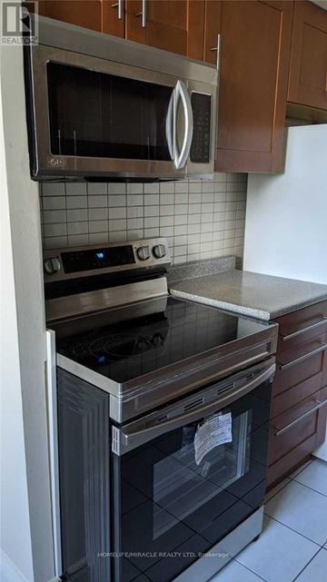Mississauga (Applewood) condo for rent - A modern kitchen with a stainless steel oven and microwave above a black stove.