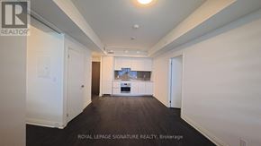 Mississauga (City Centre) condo for rent - A white room with a kitchen in the background and a brokerage sign on the wall.