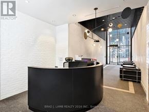 Toronto (Moss Park) condo for rent - A reception area with a black counter and a white wall.