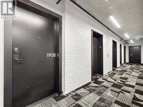 Toronto (Moss Park) condo for rent - A hallway with a black door on the left and three other black doors in the distance.