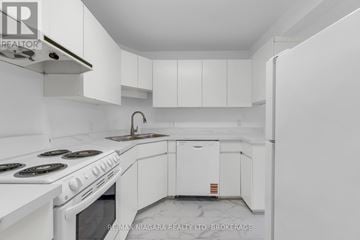 Pelham (Fenwick) multi-family for rent - A white kitchen with a stove top oven and white cabinets.