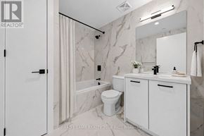 Toronto (Moss Park) condo for rent - A white bathroom with a marble wall and a white toilet.