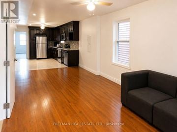 Toronto (South Riverdale) apartment for rent - A living room with a black couch and wooden floors.