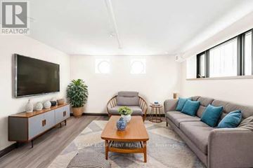 Hamilton (Beasley) condo for rent - A living room with a grey couch, a wooden coffee table, and a television mounted on the wall.