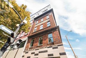 Hamilton (Beasley) condo for rent - A tall building with a brick facade and a sign that reads "RRB REAL ESTATE INC. Brokerage".