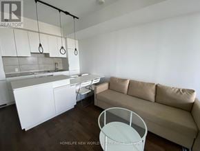 Toronto (Bay Street Corridor) condo for rent - A living room with a couch, a table, and a kitchen area in the background.