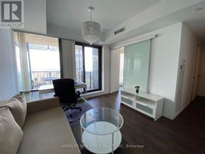 Toronto (Bay Street Corridor) condo for rent - A living room with a couch, a chair, and a table with a vase of flowers on it.