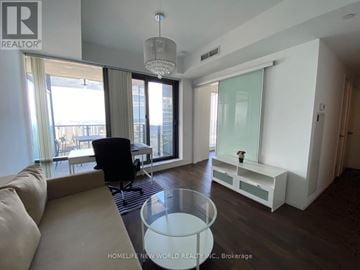 Toronto (Bay Street Corridor) condo for rent - A living room with a couch, a chair, and a table with a vase of flowers on it.