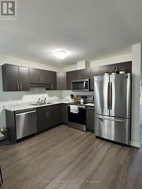 Thorold (Hurricane/Merrittville) townhouse for rent - A modern kitchen with stainless steel appliances and dark wood cabinets.