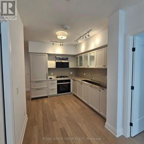 Toronto (Englemount-Lawrence) condo for rent - A kitchen with white cabinets and a wooden floor.