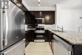 Toronto (Don Valley Village) condo for rent - A modern kitchen with a stainless steel refrigerator and dark brown cabinets.