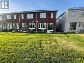 Pickering townhouse for rent - A grassy field in front of a row of houses with a REALTOR sign.