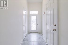 Oakville (Go Glenorchy) townhouse for rent - A hallway with white walls and a tiled floor leading to a door.