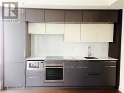 Toronto (Bay Street Corridor) condo for rent - A modern kitchen with white cabinets and stainless steel appliances.