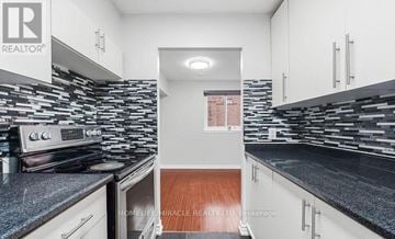 Toronto (West Hill) townhouse for rent - A kitchen with white cabinets and a black countertop.