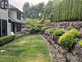 West Vancouver apartment for rent - A house with a stone wall and green plants in front.