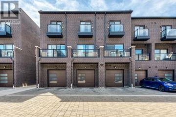 Toronto (Rustic) townhouse for rent - A blue car is parked in front of a brick building with multiple garage doors.