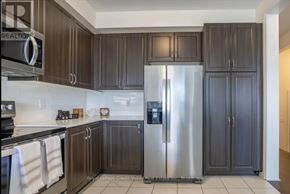 Innisfil (Alcona) apartment for rent - A kitchen with dark wood cabinets and a stainless steel refrigerator.