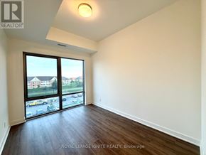 Clarington (Bowmanville) condo for rent - A room with a large window and wooden flooring.
