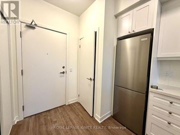 Clarington (Bowmanville) condo for rent - A kitchen with white cabinets and a stainless steel refrigerator.