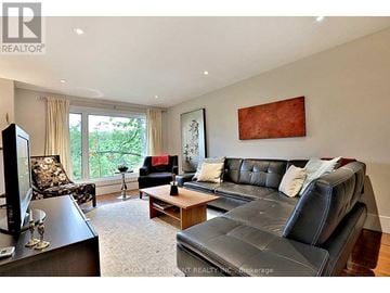 Burlington (Bayview) apartment for rent - A living room with a black leather couch and a painting on the wall.