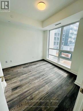 Richmond Hill (South Richvale) condo for rent - A room with wood flooring and a window overlooking a city.