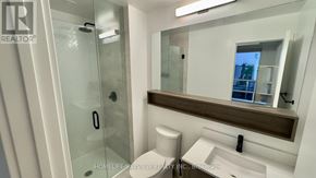 Richmond Hill (South Richvale) condo for rent - A modern bathroom with a glass shower door and a large mirror above the sink.