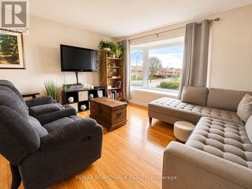Ottawa apartment for rent - A living room with a grey couch, a grey sofa, a grey chair, a grey ottoman, a grey coffee table, a grey TV stand, a grey plant, a grey wall, a grey window, a grey curtain,