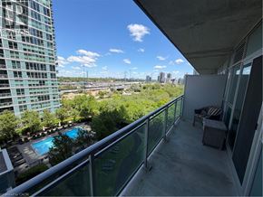 Toronto condo for rent - A balcony with a chair and a table overlooking a pool and a cityscape.