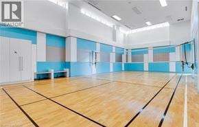 Toronto condo for rent - A large indoor badminton court with wooden flooring and a net.