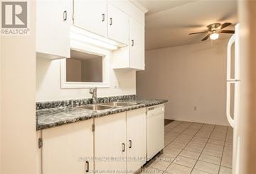Chatham-Kent condo for rent - A kitchen with white cabinets and a marble countertop.