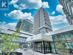 Toronto (Mimico) house for rent - A modern building with glass windows and a sign that reads "251" is surrounded by other buildings.