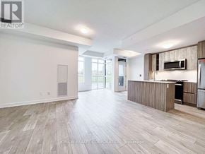 Toronto (Mimico) house for rent - A spacious living room with wood flooring and a kitchen area with stainless steel appliances.