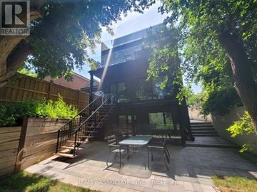 Toronto (Caledonia-Fairbank) apartment for rent - A patio with a table and chairs is surrounded by trees and a wooden fence.
