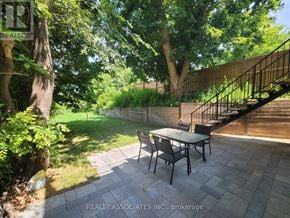 Toronto (Caledonia-Fairbank) apartment for rent - A patio with a table and chairs is surrounded by greenery.