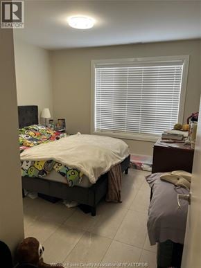 Windsor apartment for rent - A bedroom with a bed, nightstand, and window with blinds.