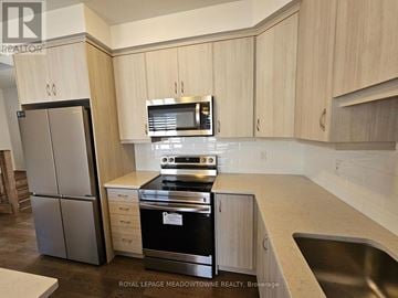 Kitchener apartment for rent - A kitchen with a stainless steel refrigerator and a stove top oven.