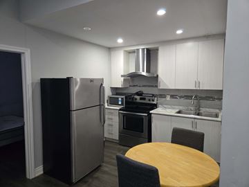 Mississauga apartment for rent - A modern kitchen with a wooden table and stainless steel appliances.