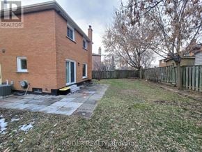 Vaughan (Brownridge) apartment for rent - A red brick house with a fence and a tree in the backyard.