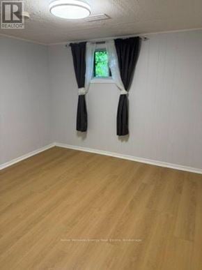 Pickering (West Shore) apartment for rent - A room with wooden flooring and a window with black curtains.