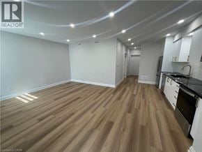 Kitchener apartment for rent - A room with wooden flooring and a kitchen area with stainless steel appliances.