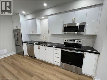 Kitchener apartment for rent - A kitchen with white cabinets and black countertops.